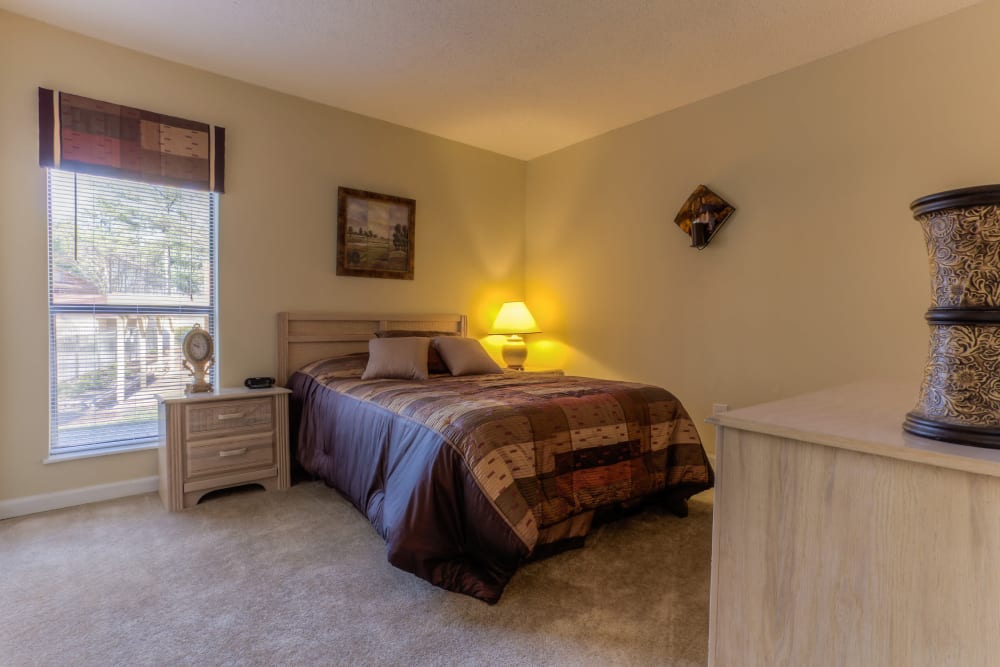 Spacious bedroom with a large window and plush carpeting at Enclave at North Point Apartment Homes in Winston Salem, North Carolina