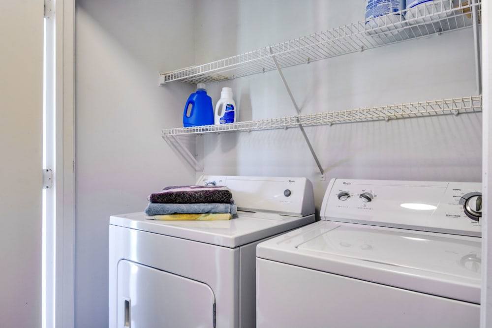 Washer and dryer room with shelving at Woodbrook Apartment Homes in Monroe, North Carolina