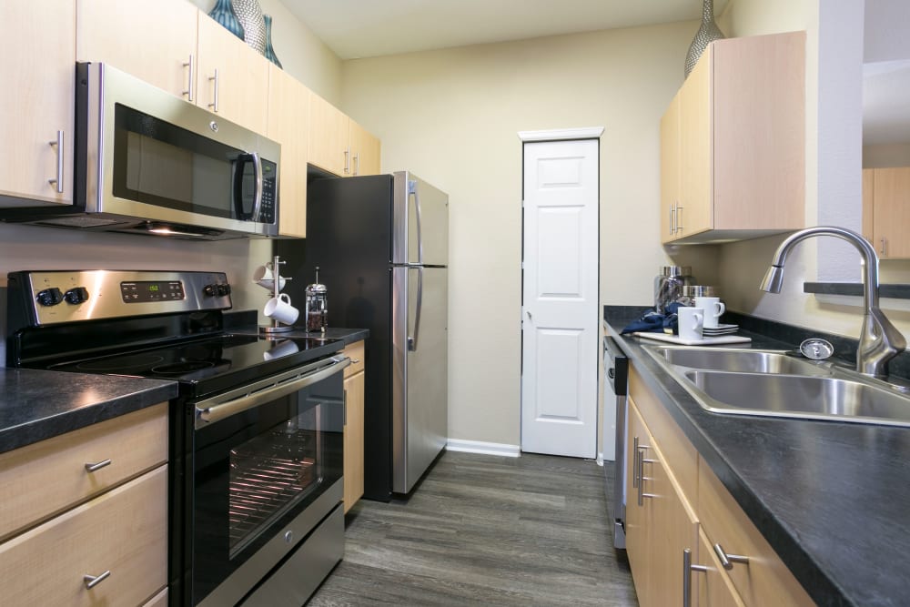 Kitchen with wood-style flooring and stainless steel appliances at Crestone Apartments in Aurora, Colorado