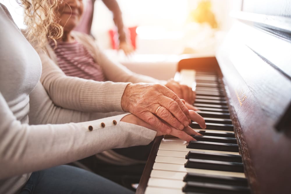 A resident plays the piano with the help of another at Arlington Place of Grundy Center in Grundy Center, Iowa