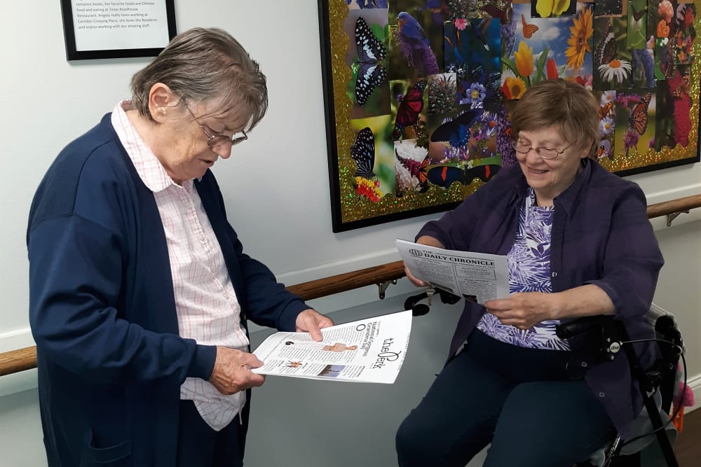 Resident friends reading the monthly news bulletin at Corridor Crossing Place in Cedar Rapids, Iowa
