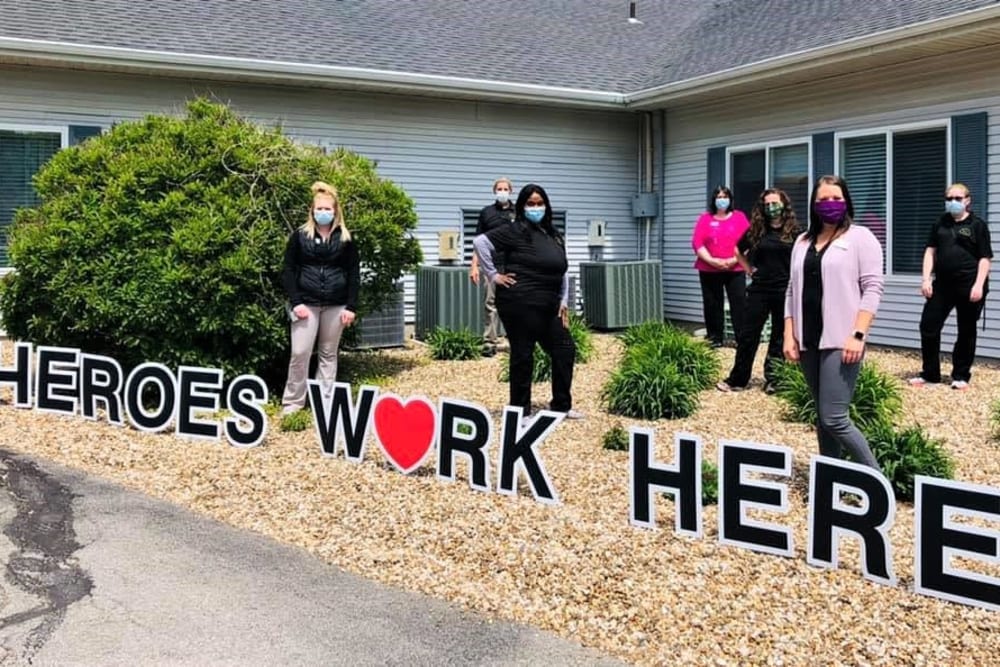 Staff pose outside building with heroes work here sign at Corridor Crossing Place in Cedar Rapids, Iowa