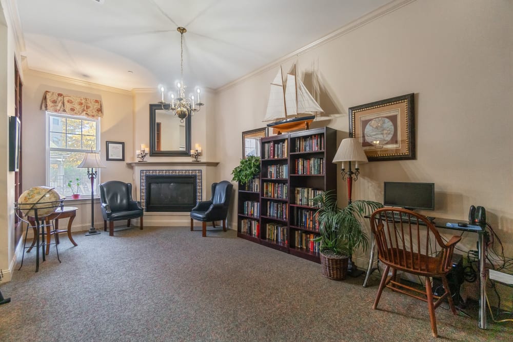 General purpose room with books, a computer, and chairs next to a fireplace at The Hearth at Gardenside in Branford, Connecticut