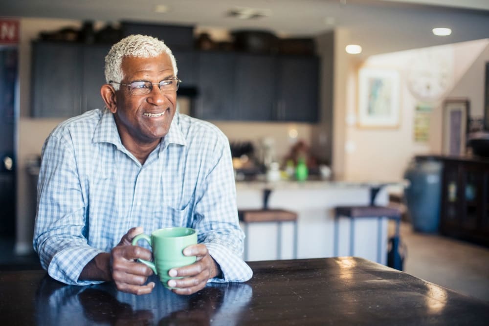 Resident enjoying coffee in his living room at Campus Commons Senior Living in Sacramento, California