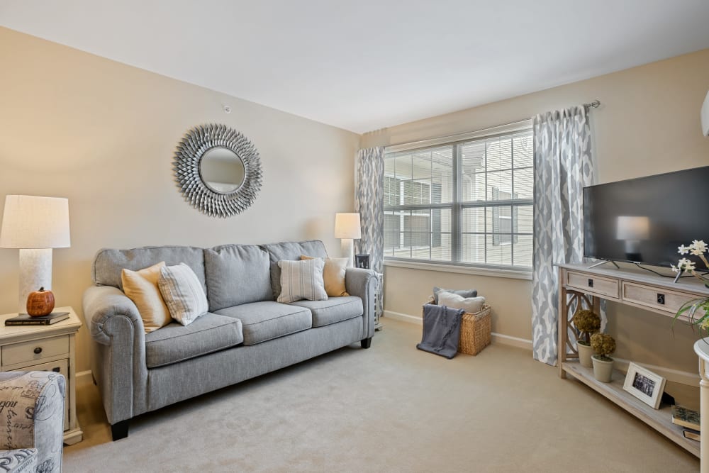 Senior apartment living room with a couch against the wall and a tv in the corner at The Hearth at Hendersonville in Hendersonville, Tennessee