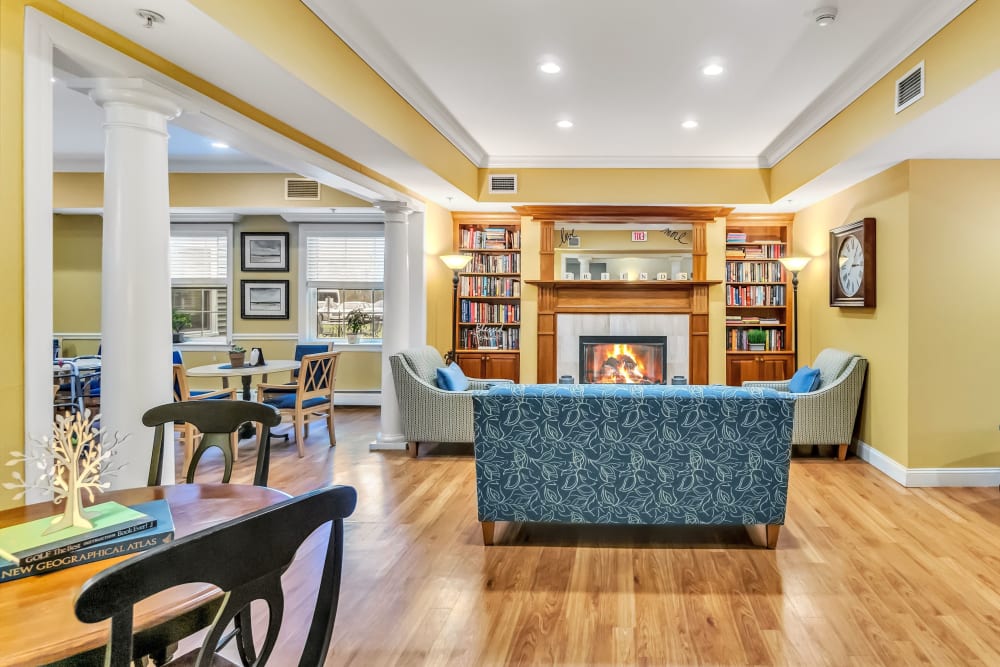 Lounge with hardwood floors, a fireplace, and a couple full bookshelves at The Hearth at Tuxis Pond in Madison, Connecticut