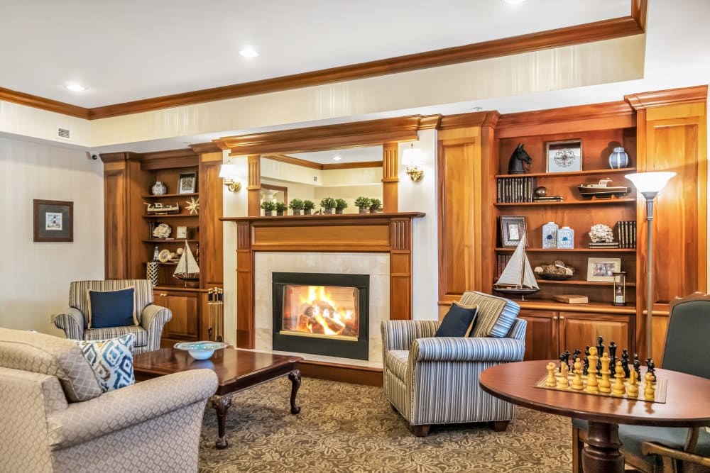 Lounge with a fireplace, several chairs, a couch, and a chess table at The Hearth at Tuxis Pond in Madison, Connecticut
