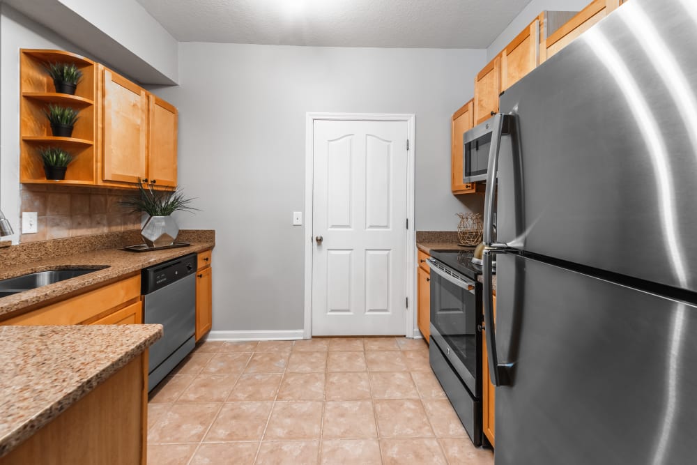 Kitchen with stainless steal appliances and wooden cabinets at Eddison at Deerwood Park in Jacksonville, Florida