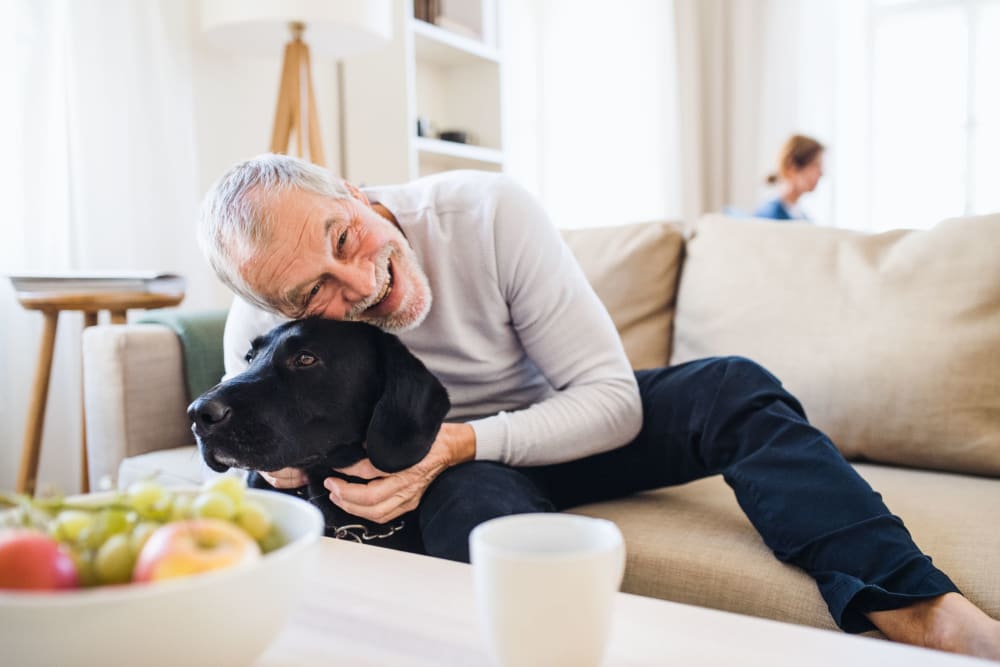Man snuggling with his dog in his living room at Fairview Senior Apartments in Rising Sun, Maryland