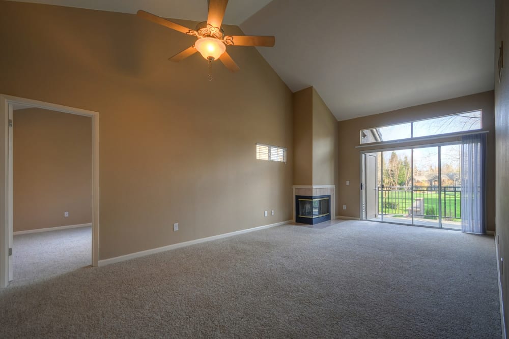A living room with plush carpeting and a ceiling fan at Larkspur Woods in Sacramento, California