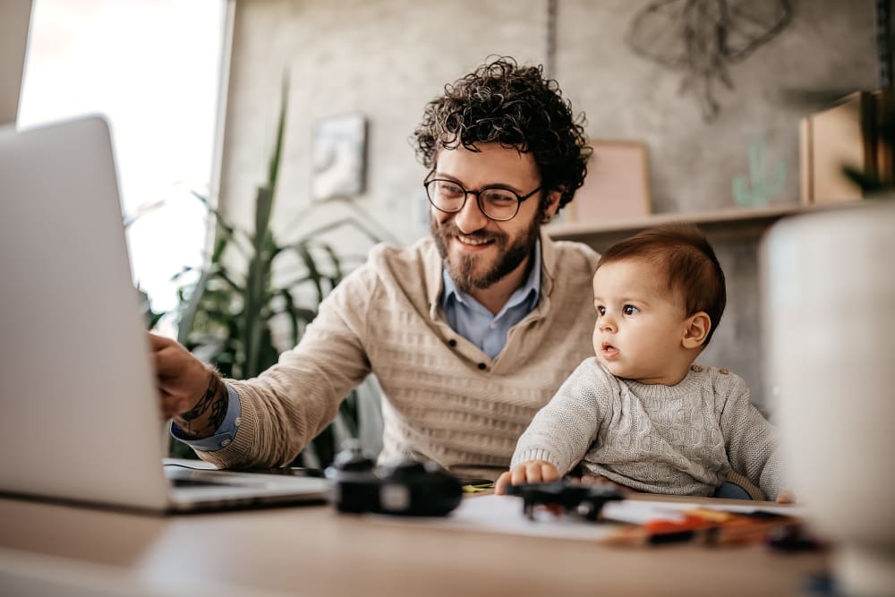 Resident working from home with his baby on his lap at Lakeview Residences in Aurora, Illinois