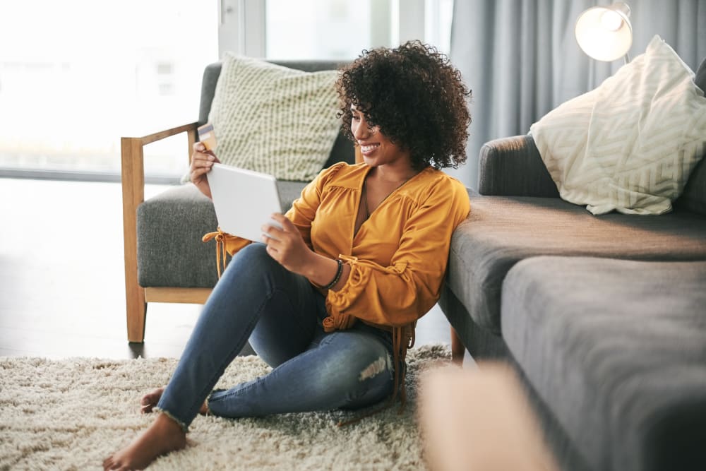 Resident looking at her tablet while sitting on the floor at Lakeview Residences in Aurora, Illinois