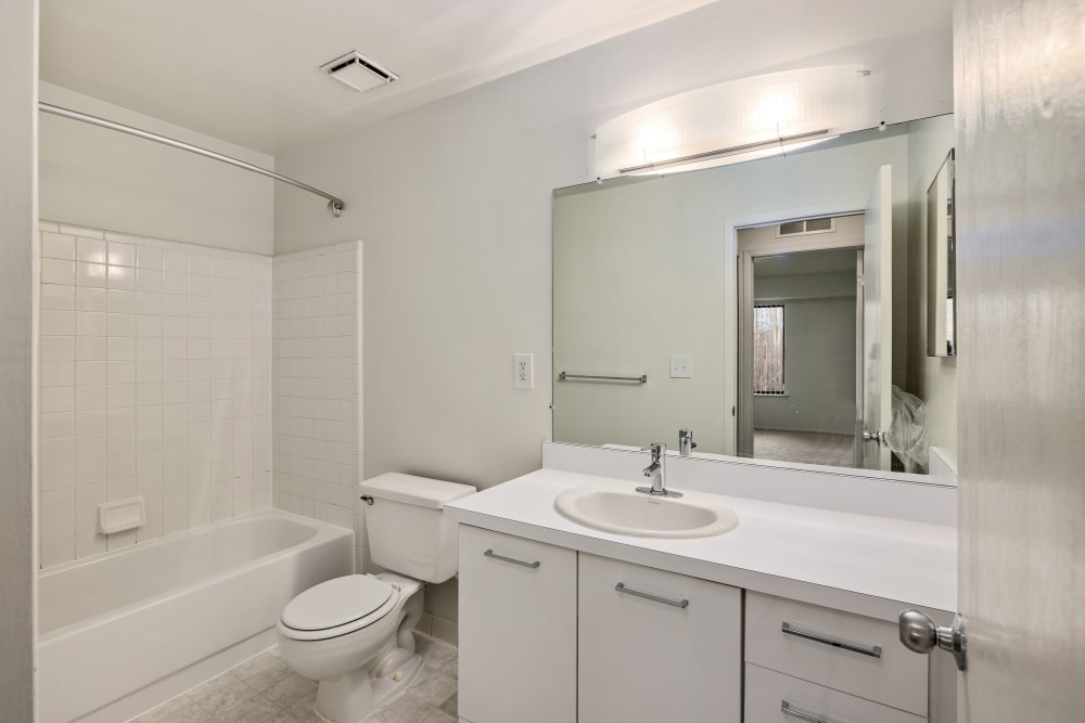 Bathroom with a tub/shower and vanity with white cabinets at Farmington Oaks Apartments in Farmington, Michigan