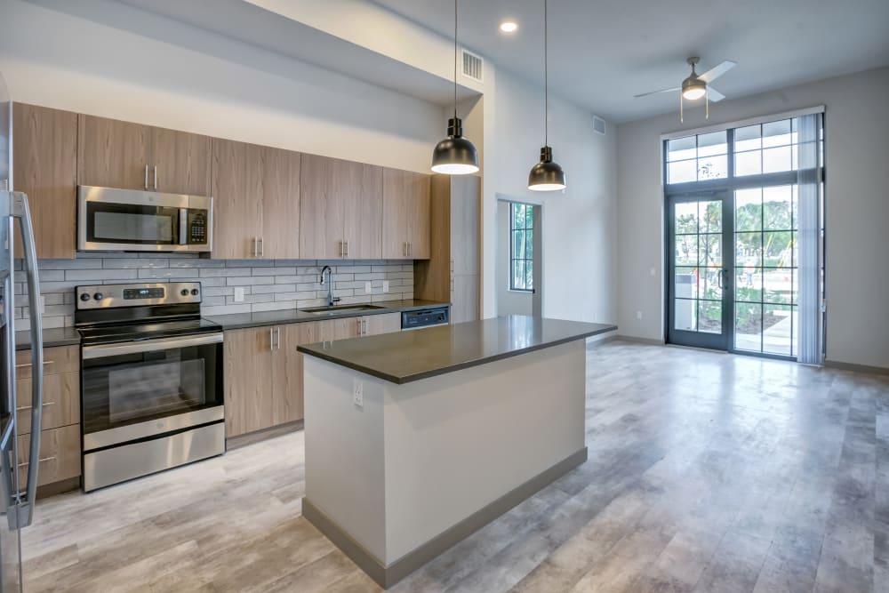 Kitchen with large island and floor to ceiling windows at The District Flats in West Palm Beach, Florida