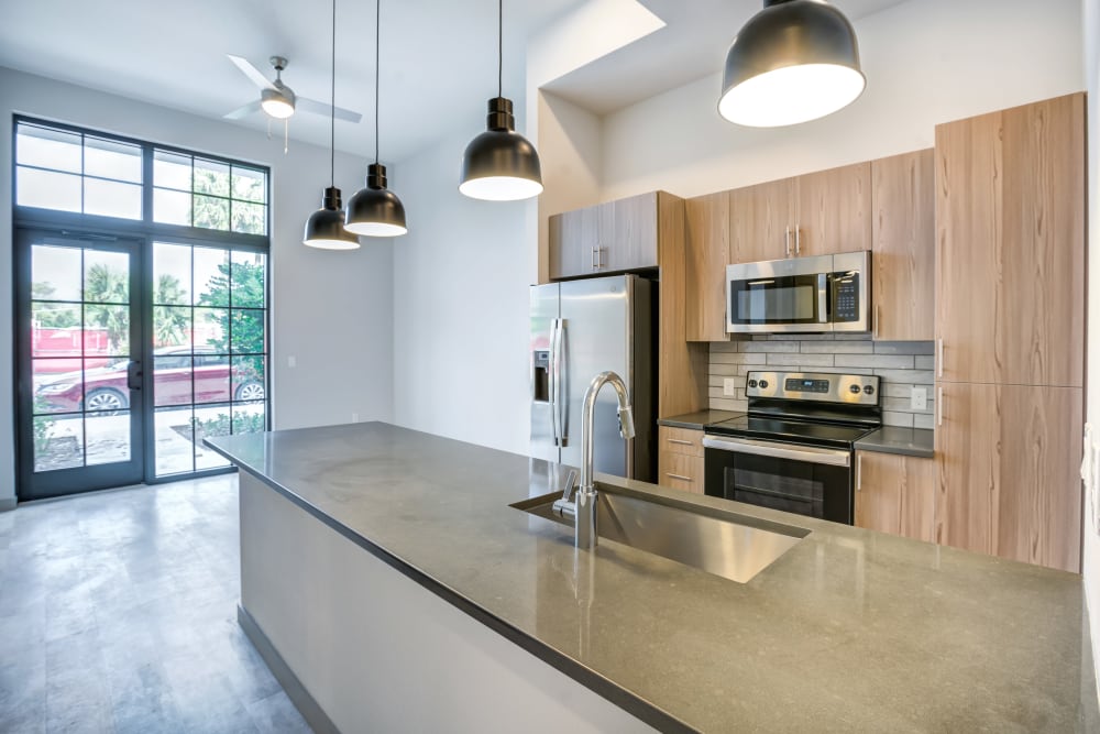 Kitchen with large island and overhead lighting at The District Flats in West Palm Beach, Florida