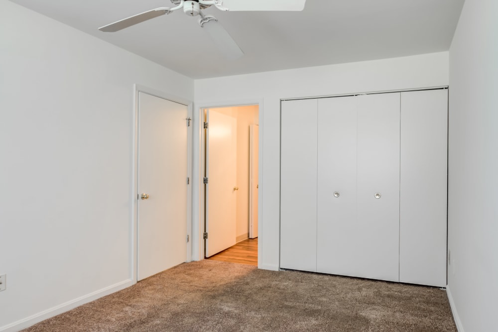 A bedroom with a ceiling fan and a large closet at The Vinings at Christiana in Newark, Delaware