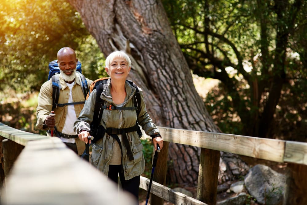 Two residents hiking and crossing a bridge on a trail near Applewood Pointe of Westminster in Westminster, Colorado