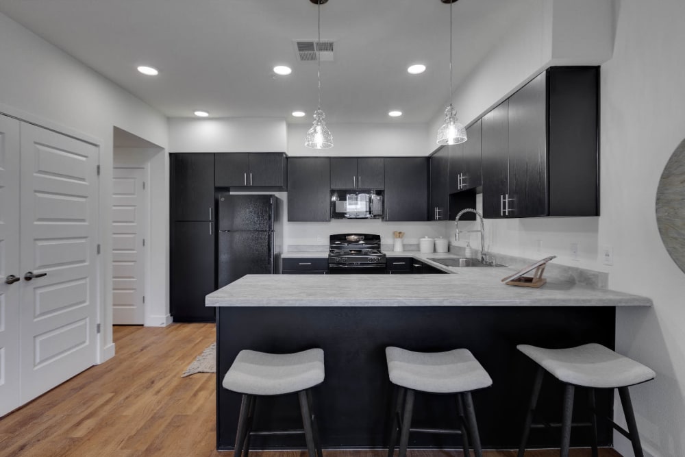 Island with quartz countertop and hardwood-inspired flooring in a model home's kitchen at Olympus Rodeo in Santa Fe, New Mexico