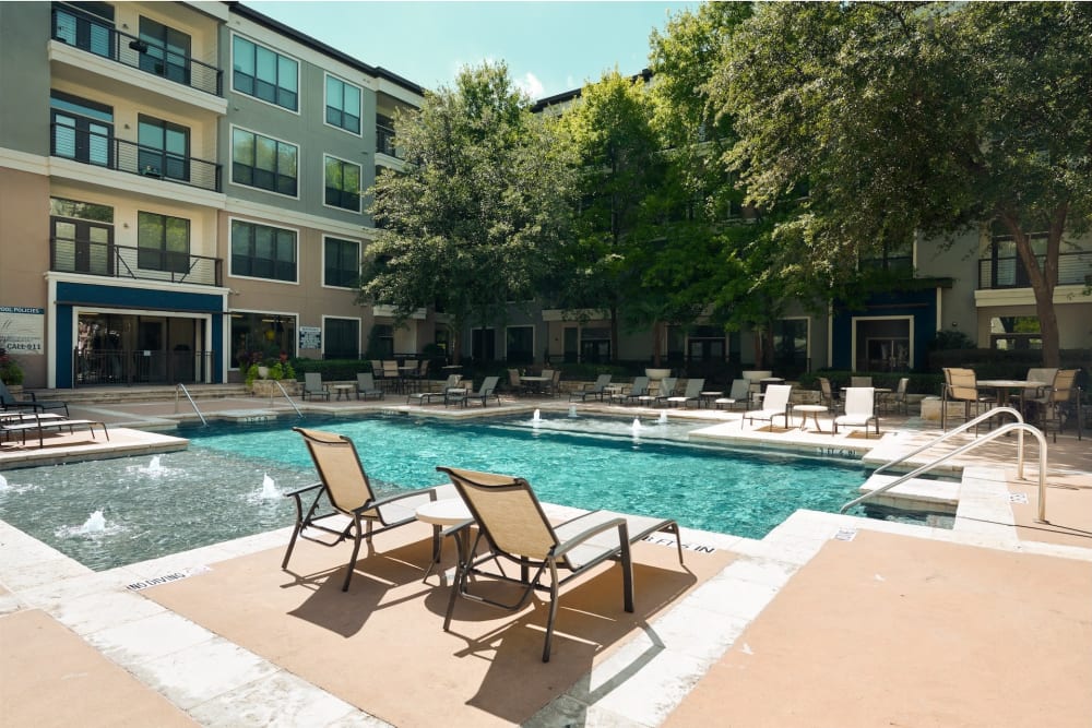 Beautiful resort style swimming pool surrounded by lounge chairs at Seville Uptown in Dallas, Texas