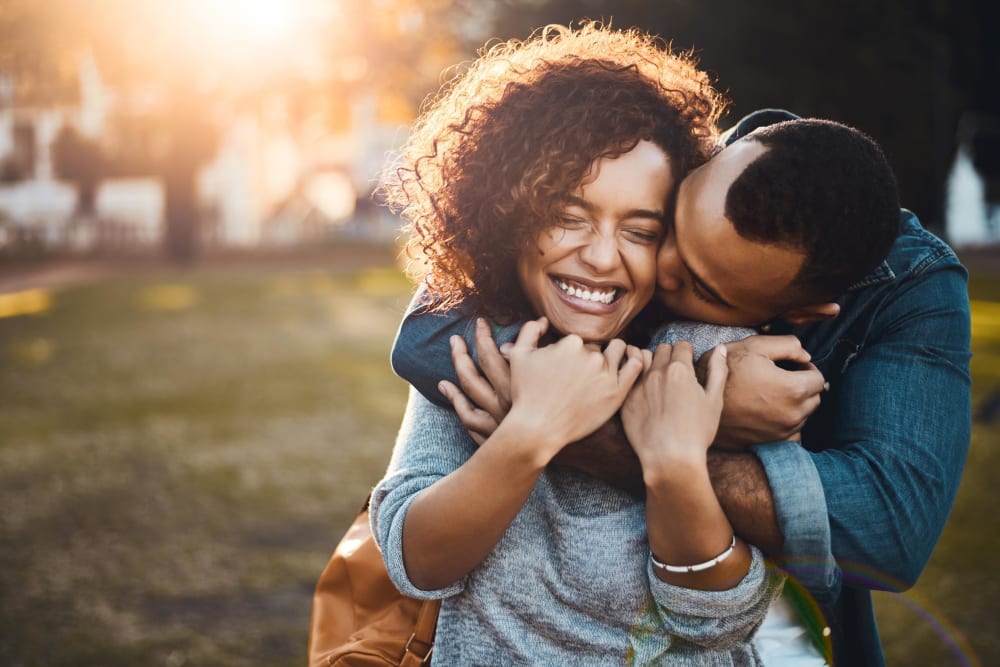Couple holding each other and kissing on the cheek near Vidorra McKinney Avenue in Dallas, Texas
