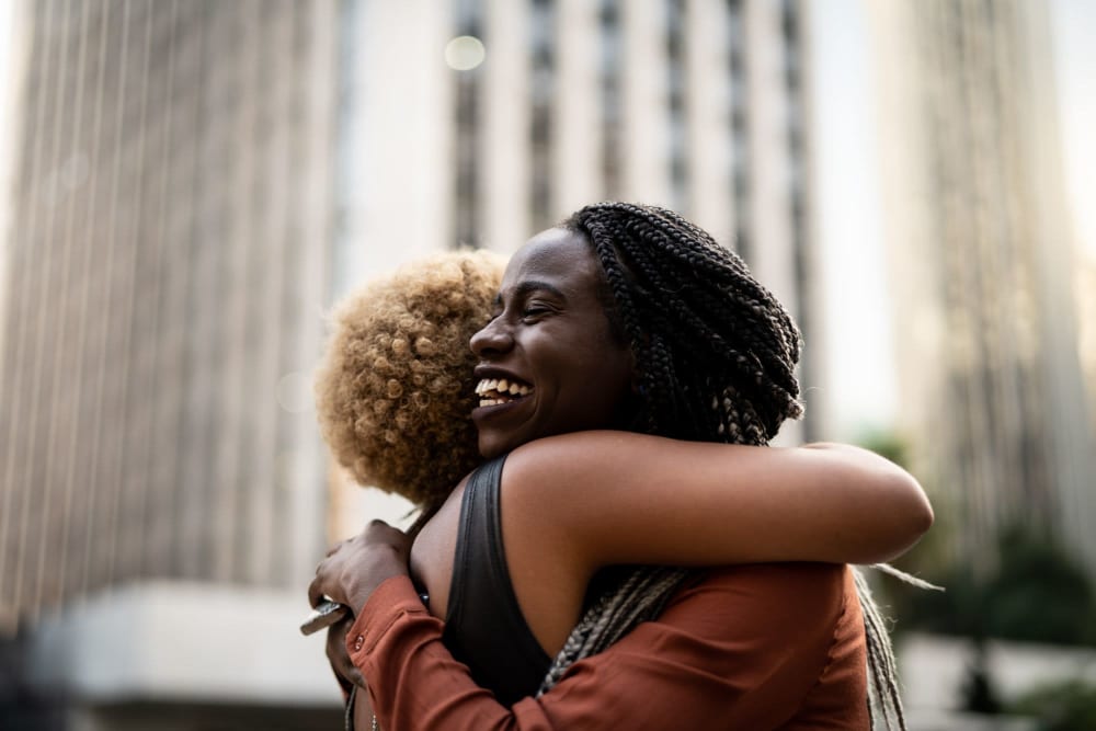 Two friends hugging each other out in the neighborhood near Vidorra McKinney Avenue in Dallas, Texas