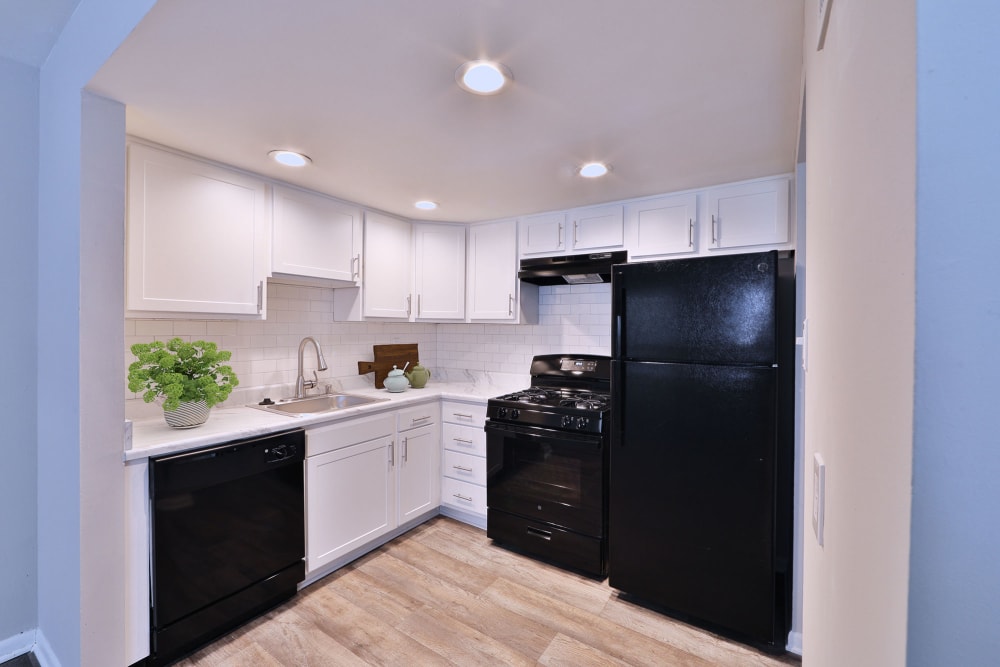 Kitchen with white cabinets and black appliances at Village Square Apartments & Townhomes in Glen Burnie, Maryland