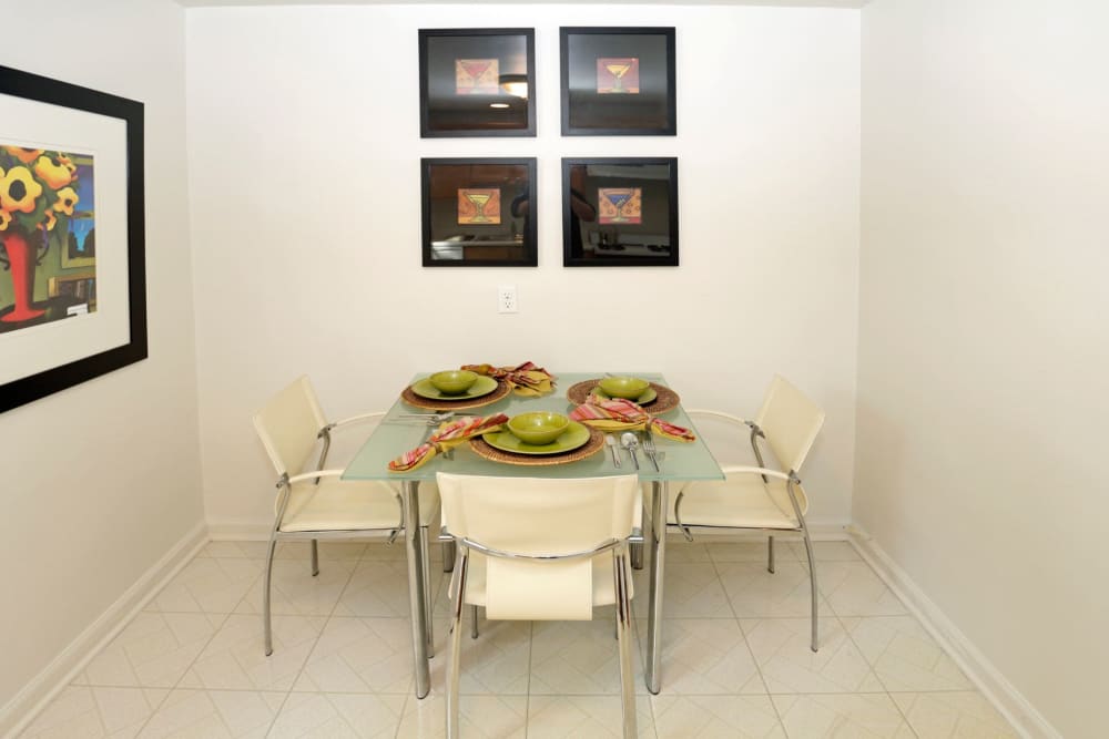 Dining area with small table and four chairs in model home at Brookchester Apartments in New Milford, New Jersey