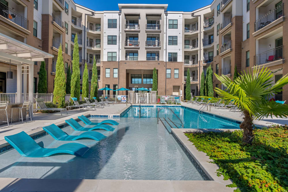 Sparkling resort style pool with deck lounge chairs in shallow pool area at Marq at Crabtree in Raleigh, North Carolina