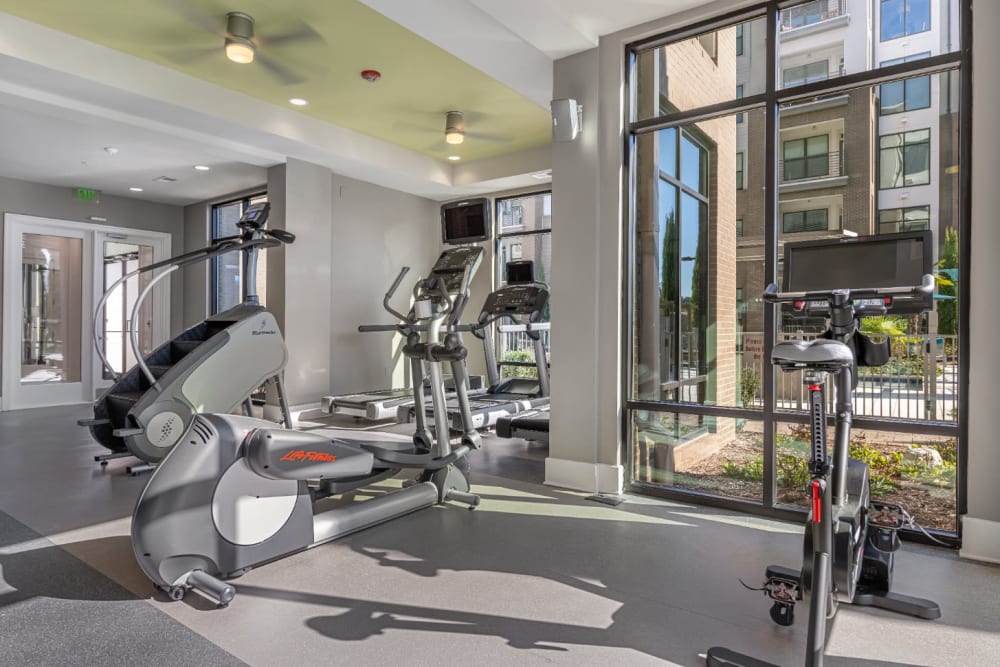 Cardio machines facing large windows in fitness room at Marq at Crabtree in Raleigh, North Carolina