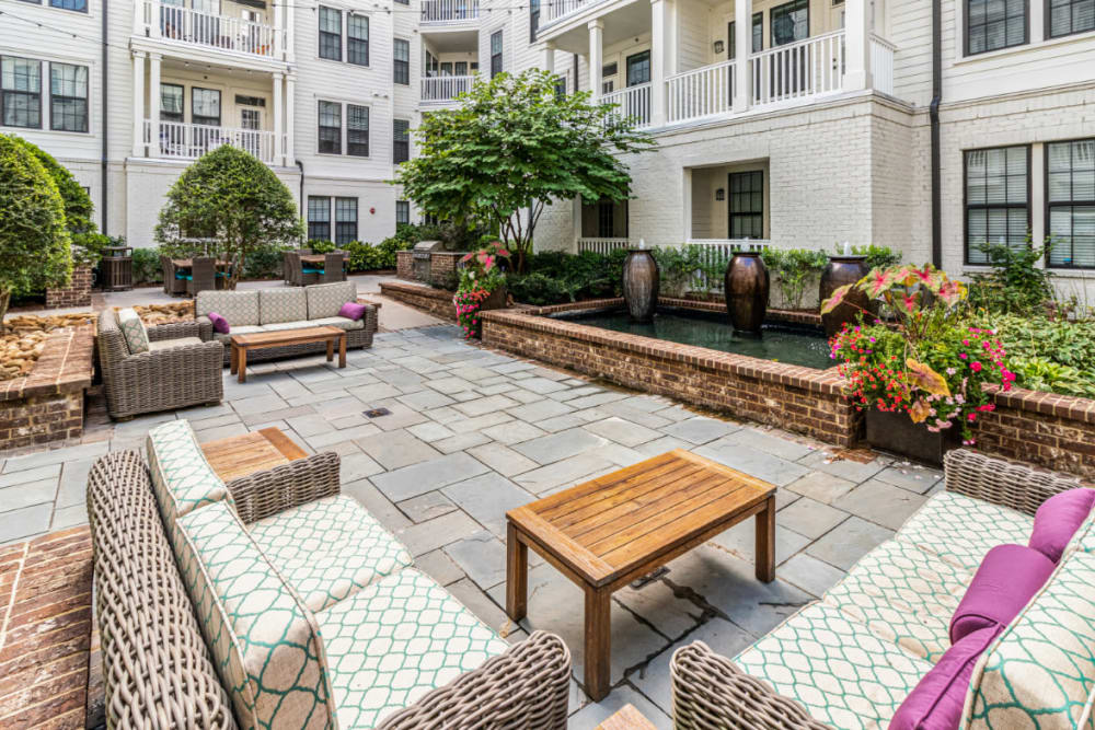 Cushioned couches and coffee tables in front of outdoor water feature at Marquis at Buckhead in Atlanta, Georgia