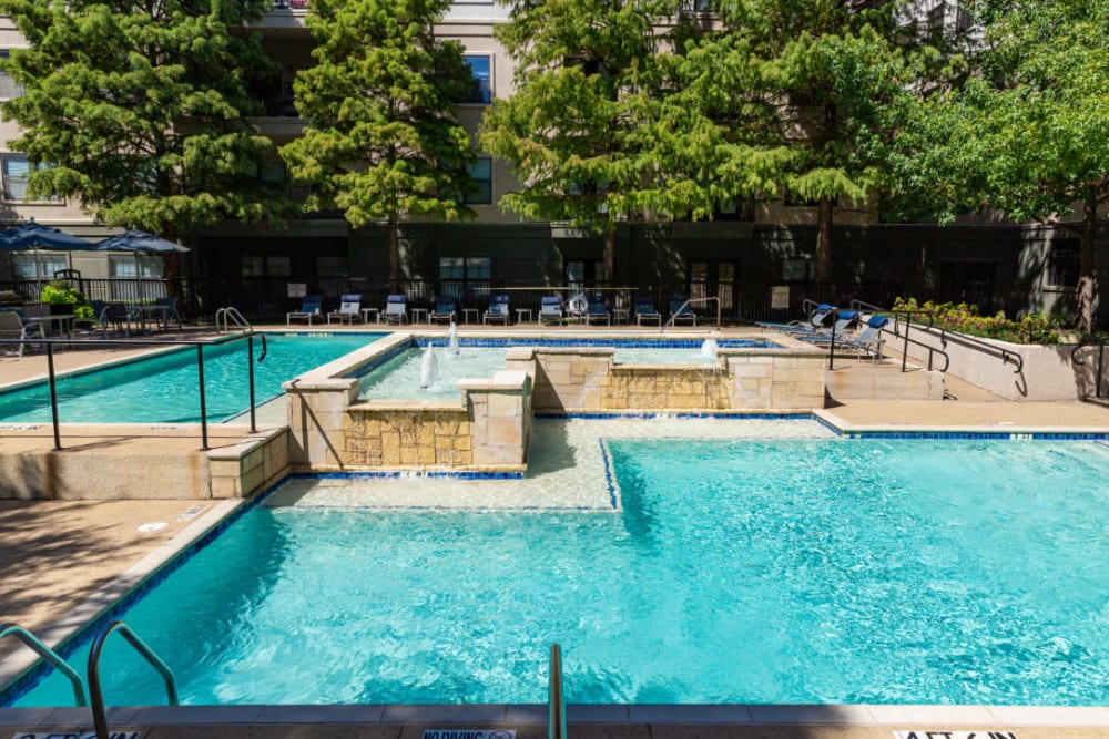 Water feature in center of sparkling pool with lounge chairs in back at Marquis at Texas Street in Dallas, Texas
