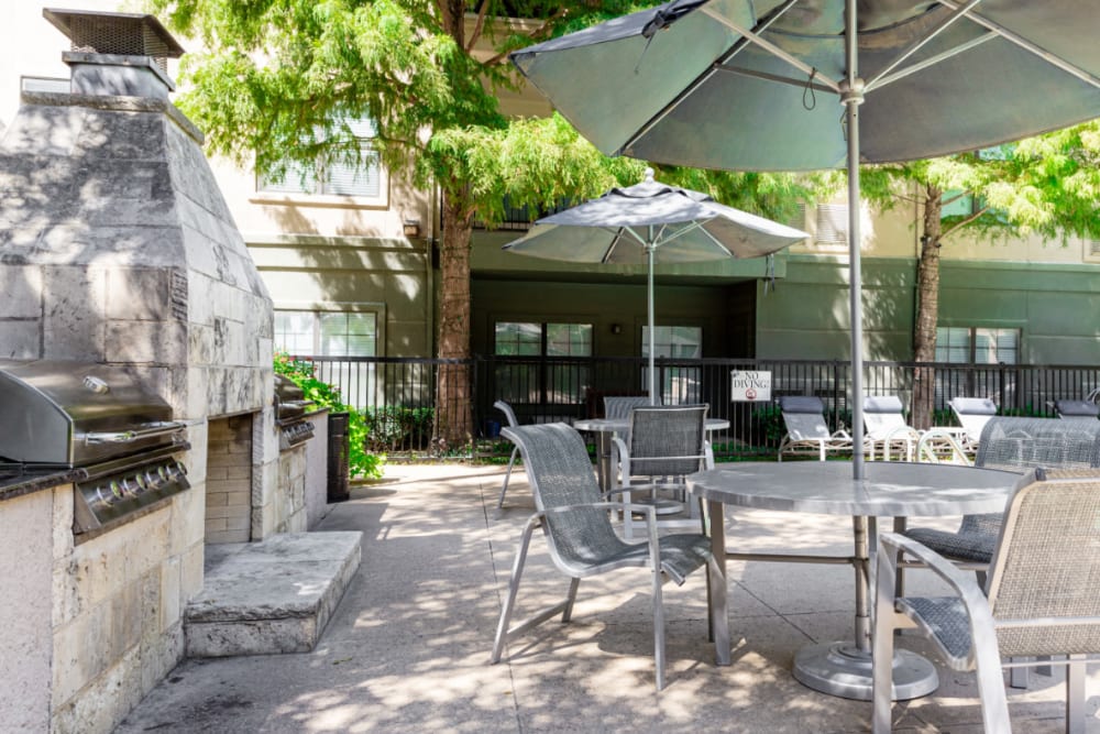 Outdoor stainless steel BBQ, fireplace, and dining tables and chairs at Marquis at Texas Street in Dallas, Texas