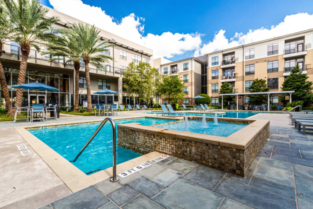 Pool deck with water feature and lounge chairs at The Marq on Voss in Houston, Texas