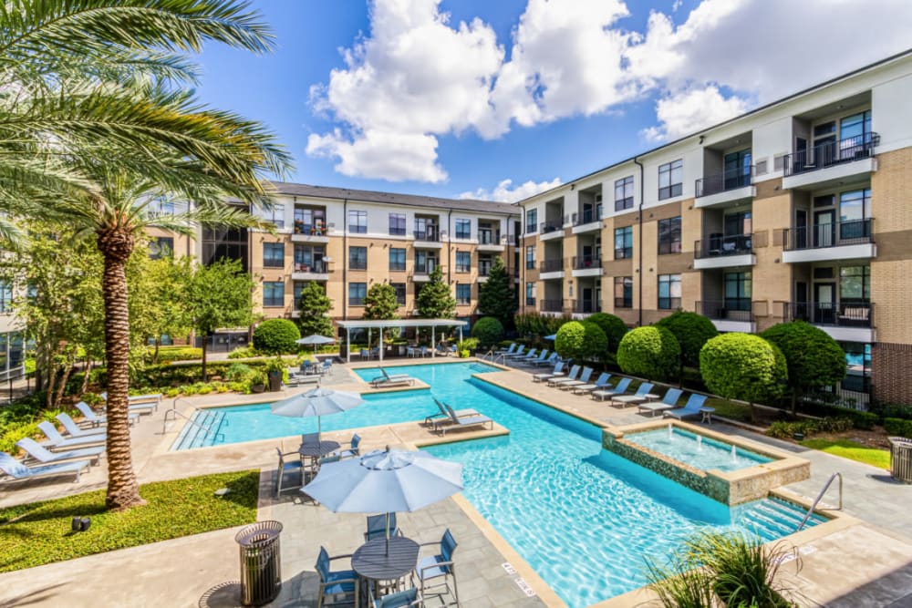 Sparkling resort style pool surrounded by building units at The Marq on Voss in Houston, Texas