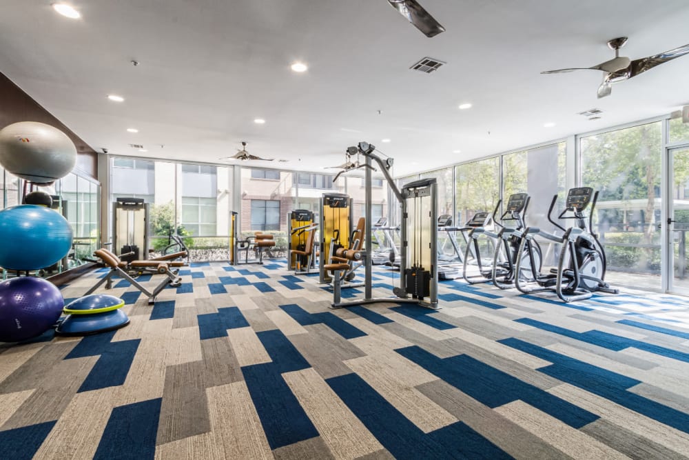 Large fitness room with medicine balls, cardio machines, and assisted weight machines at The Marq on Voss in Houston, Texas