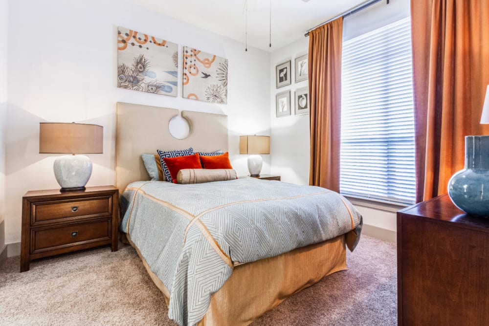 Carpeted bedroom with large bed, modern furniture, and large window at The Marq on Voss in Houston, Texas