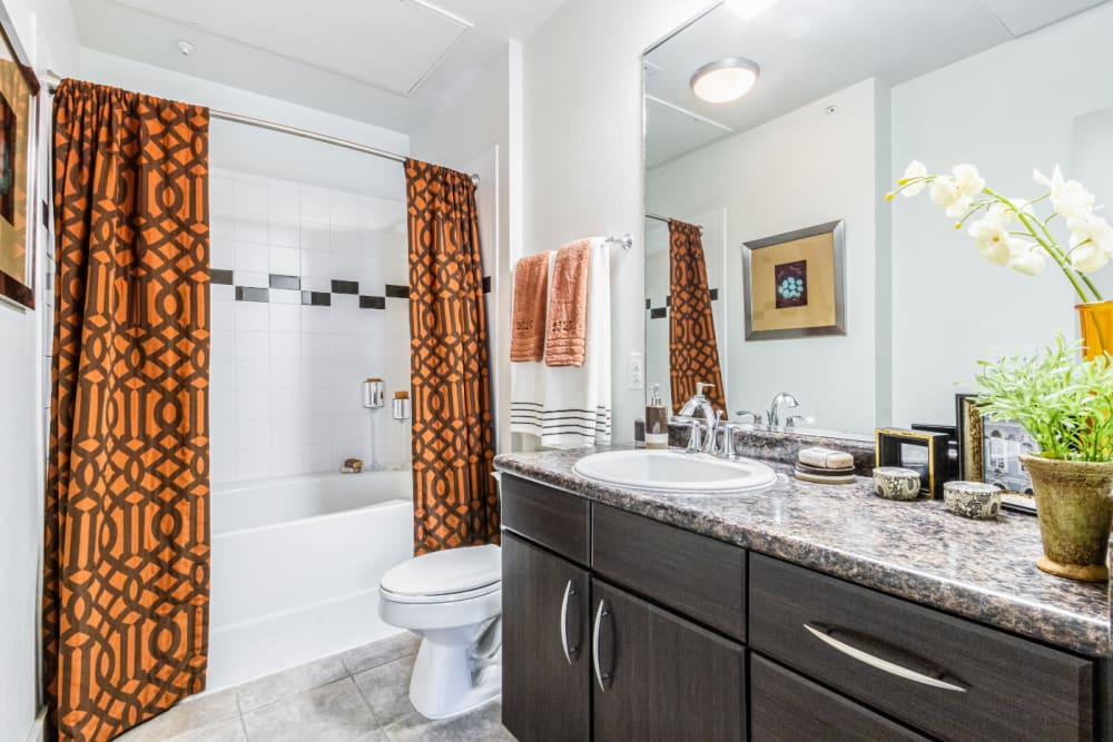 Bright bathroom with tall bathtub and granite counter at The Marq on Voss in Houston, Texas