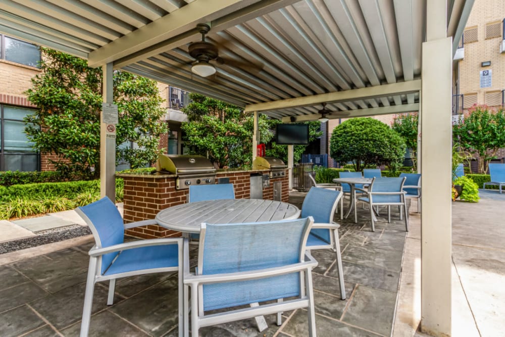 Covered BBQ area with dining tables and seats at The Marq on Voss in Houston, Texas