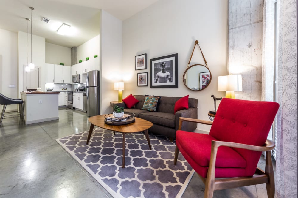 Open living room with modern furnishings and bright kitchen in background at Marq on Burnet in Austin, Texas