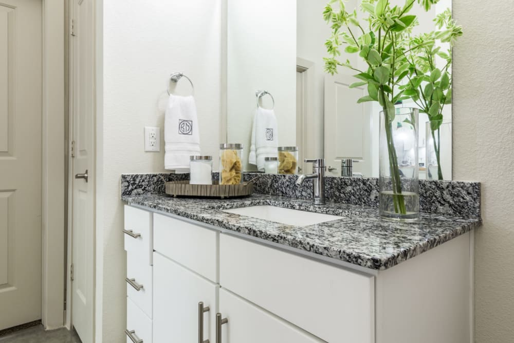 Granite counter bathroom sink with white cabinets and mirror at Marq on Burnet in Austin, Texas