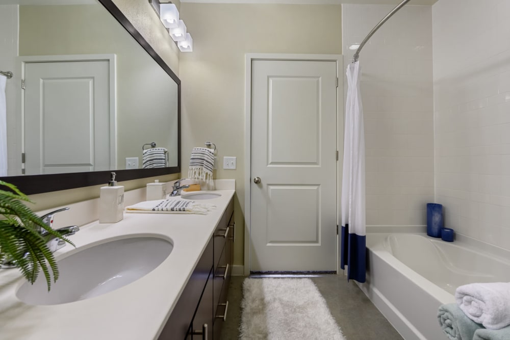 Bright bathroom with double sinks, concrete flooring, and bathtub at The 704 in Austin, Texas