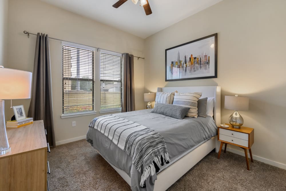 Carpeted bedroom with large bed, side tables, dresser, and windows at The 704 in Austin, Texas