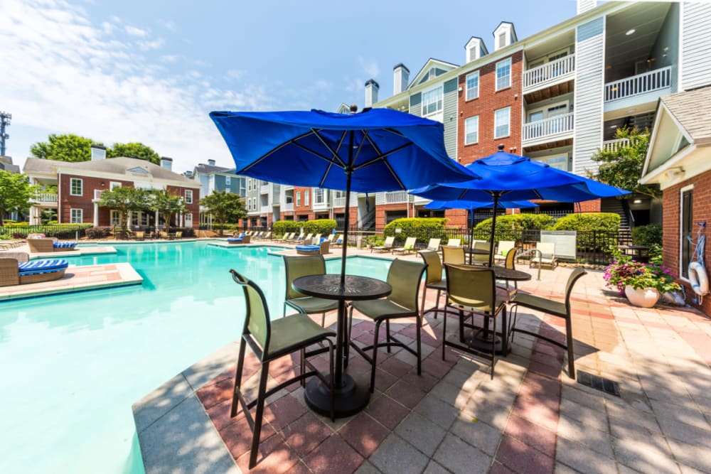 Umbrella covered dining tables and chairs on pool deck at The Marq at Brookhaven in Atlanta, Georgia