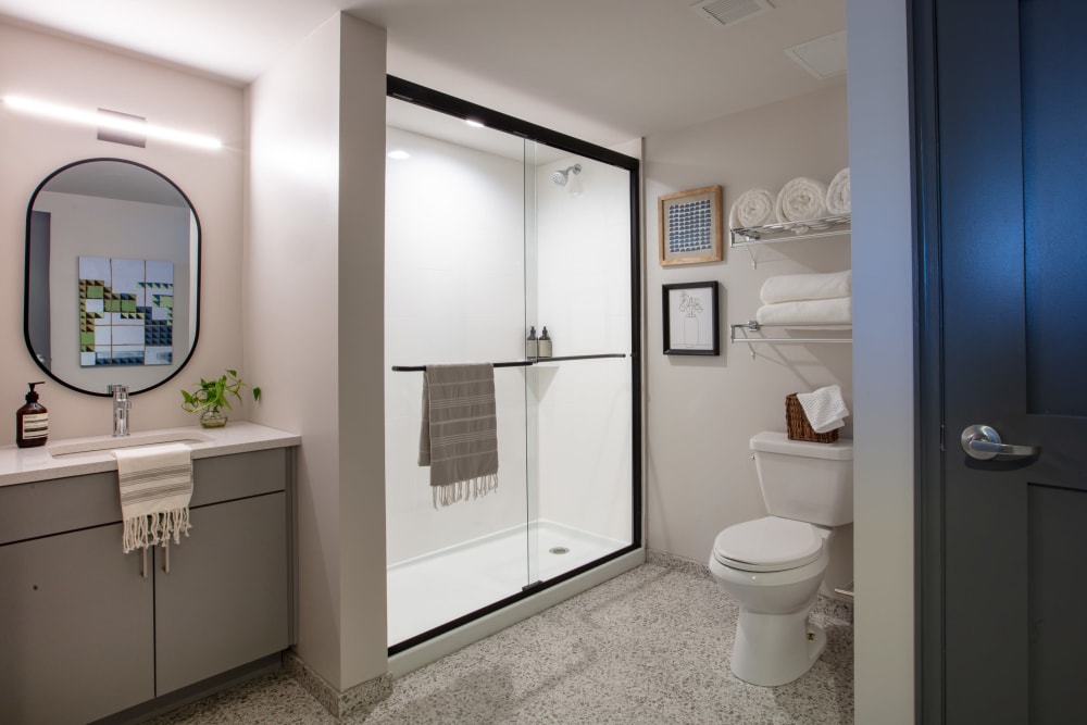 Tiled flooring and glass shower doors in a model apartment home's bathroom at Thirteen15 in New Orleans, Louisiana