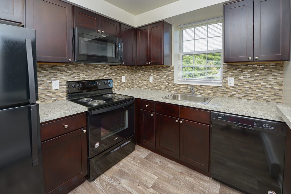 Kitchen with espresso cabinets and black appliances at Woodacres Apartment Homes in Claymont, DE