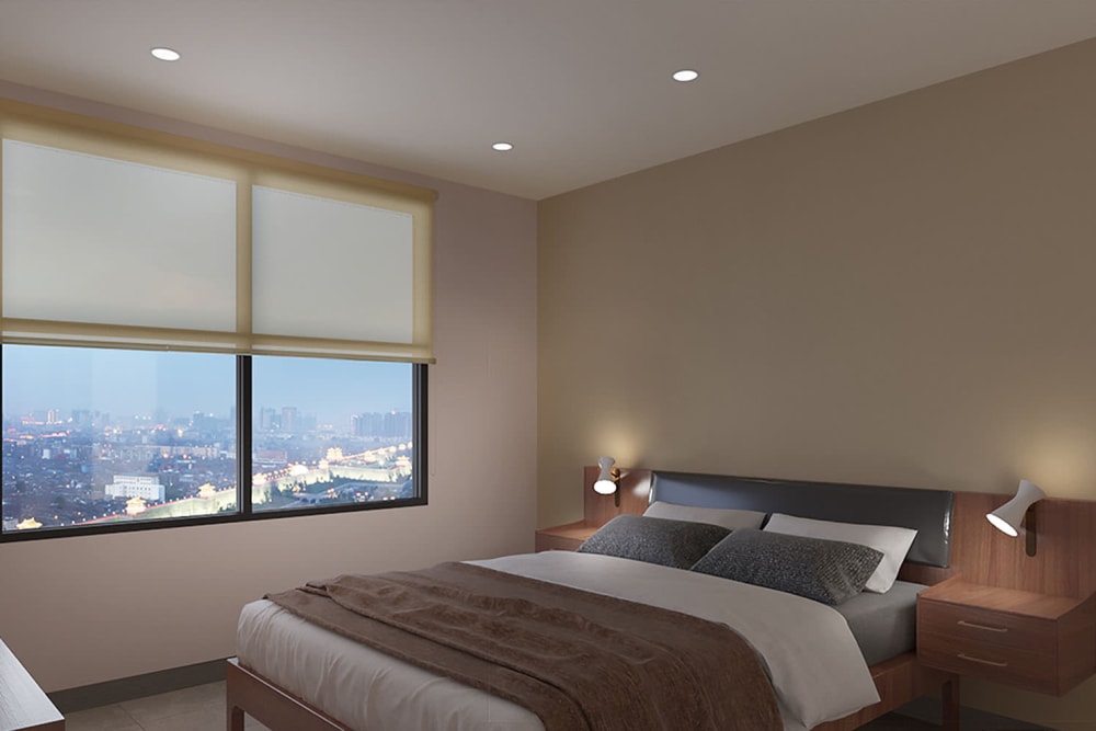 Bay window with an amazing view of the city in the well-furnished primary suite of a model apartment.
