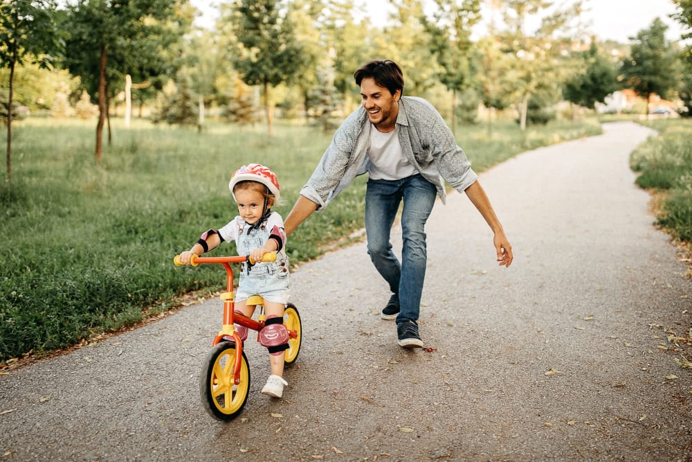 Father pushing his kid on their bike near The Galaxy in Silver Spring, Maryland