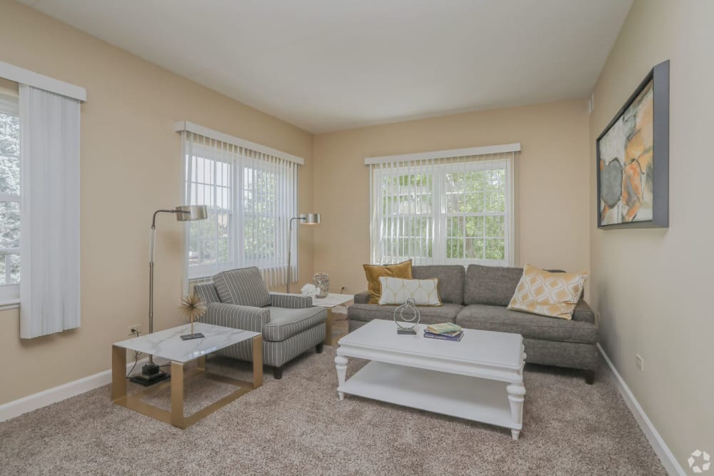 Senior apartment living room with a chair, couch, and white coffee tables at Hanover Place in Tinley Park, Illinois