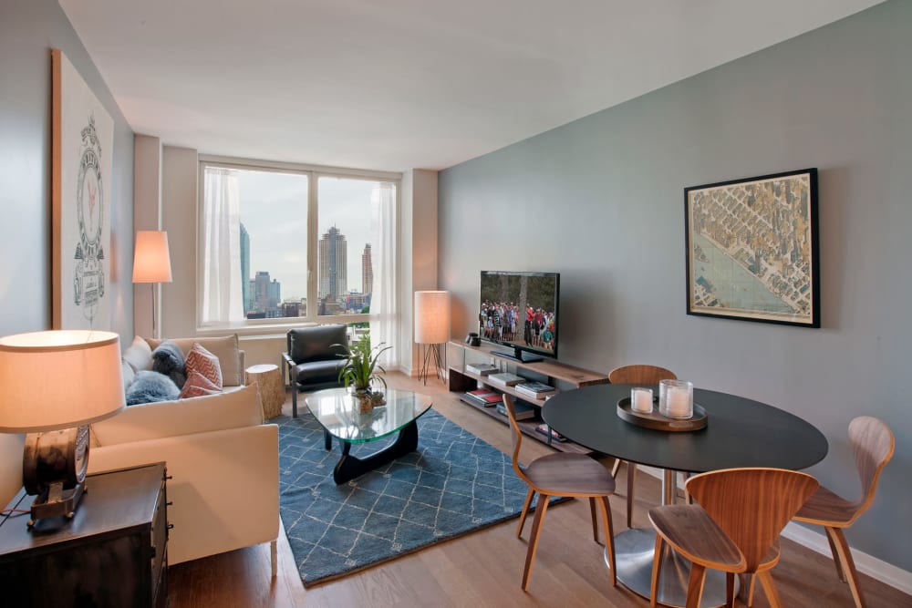 Spacious living room with a cute area rug in the middle at The Maximilian in Queens, New York