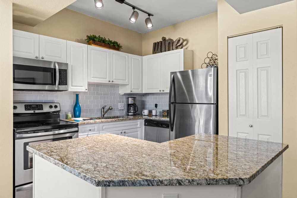 Open the kitchen with white cabinets and marble countertops at Marquis at Town Centre